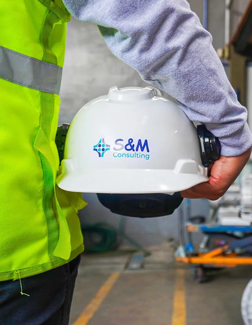 Equipo de S&M Consulting sosteniendo casco de seguridad en programa de salud ocupacional